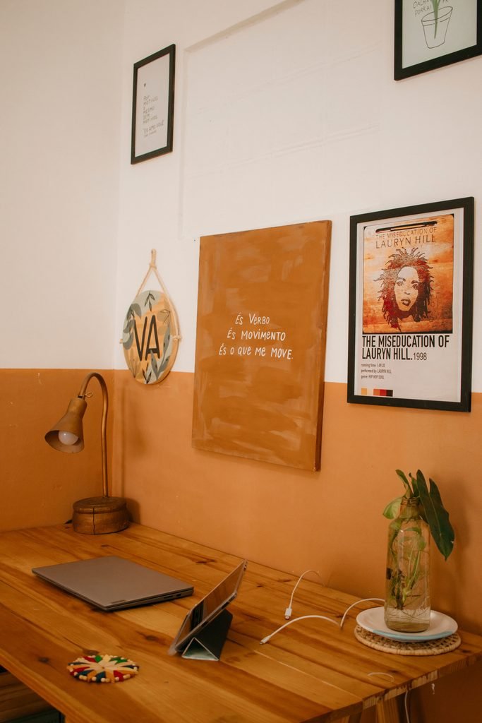 Personalized wooden desk setup with framed wall art, desk lamp, and small plant